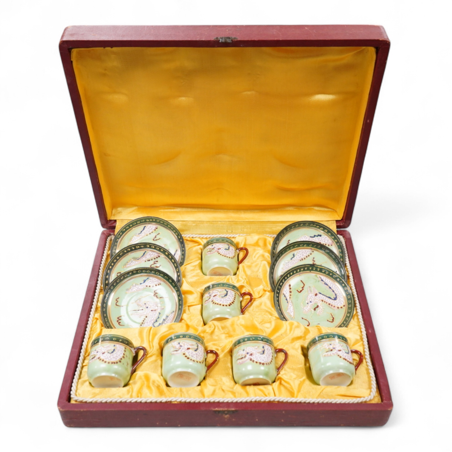 A cased Japanese coffee set, decorated with dragons on a green ground, case 34cm wide
